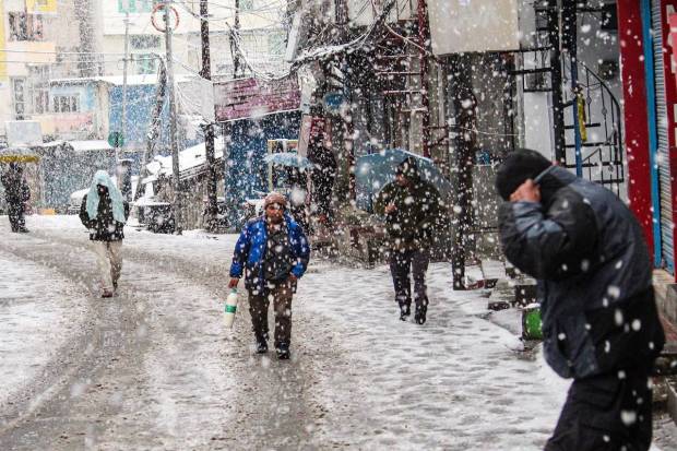 Joshimath: Commuters on a street amid heavy snowfall in Joshimath. (PTI Photo)