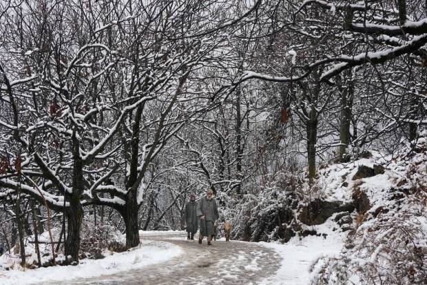Srinagar: People walk during light snowfall on the outskirts of Srinagar. (PTI Photo)