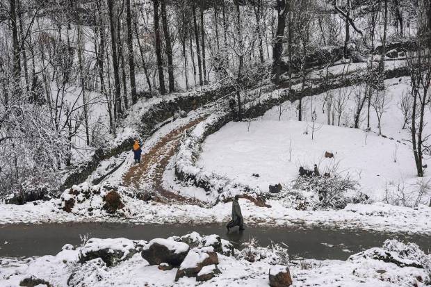 Srinagar: People walk during light snowfall on the outskirts of Srinagar. (PTI Photo)