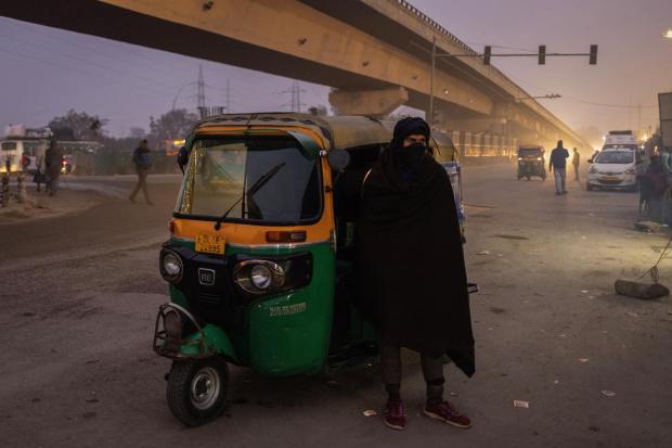 A man wrapped in a shawl waits for public transport along a road on a cold winter morning in New Delhi. (Reuters Image)