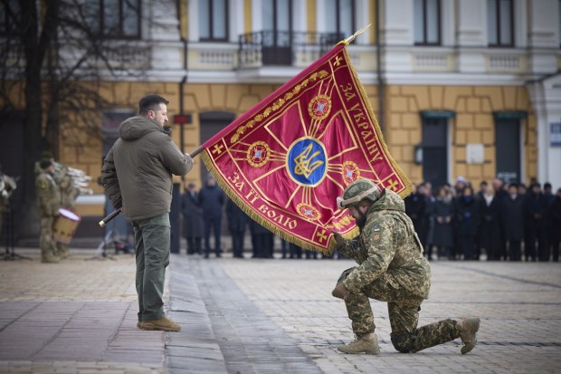 Ukrainian President Volodymyr Zelenskyy holds the flag of a military unit as an officer kisses it, during commemorative event on the occasion of the Russia Ukraine war one year anniversary in Kyiv. (AP Photo)