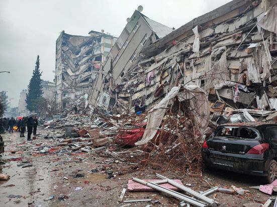 People stand in front of collapsed buildings following an earthquake in Kahramanmaras, Turkey February 6, 2023. (Photo/Reuters)