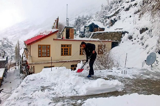 A man clears snow from his roof after a fresh spell of snowfall in Lahaul and Spiti district. (Image: PTI photo)