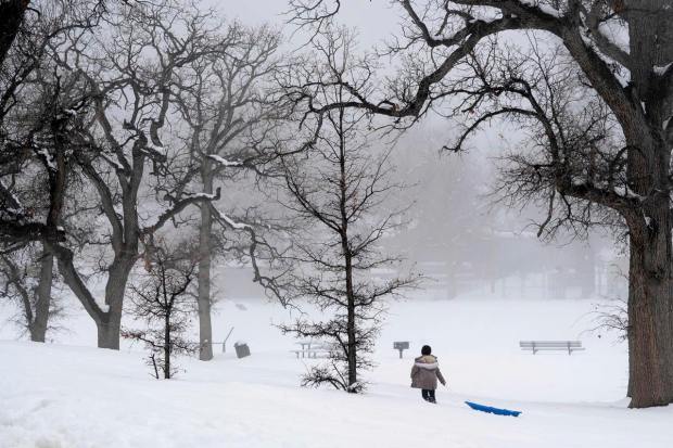 A person drags a sled through the snow at Frazier Park Monday, Feb. 27, 2023, in Calif. A winter storm warning is in effect for the area through Wednesday. (David Crane/The Orange County Register via AP)