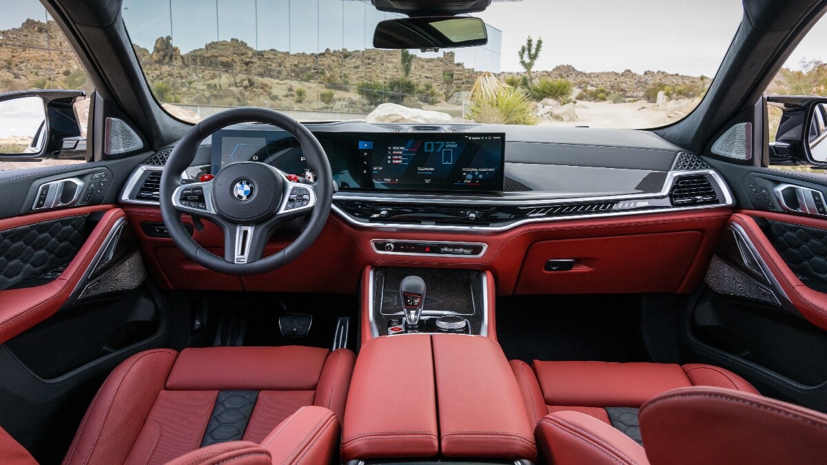 Features include an ambient light bar with M logo to its graphic, plus the M leather steering wheel with its new carbon gearshift paddles. Image shows interior of the X6 M Competition.