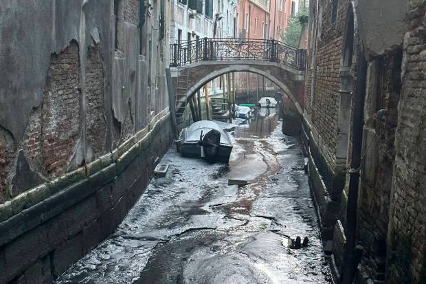 Boats are docked on a dry canal during a low tide in Venice, Italy. (AP Photo)