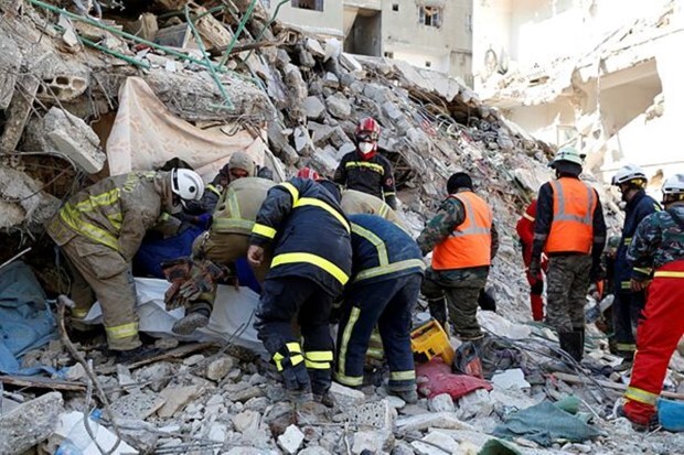 Rescue teams carry the body of a victim from a destroyed building after a devastating earthquake rocked Syria and Turkey, in the costal town of Jableh, Syria, Thursday, Feb. 9, 2023. (Image: AP Photo/Omar Sanadiki)