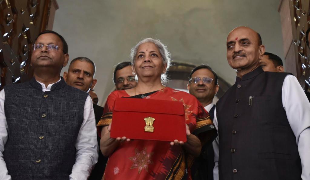 Indian Finance Minister Nirmala Sitharaman, in red, poses for the media holding a pouch containing a digital tablet, with Junior finance ministers Pankaj Chaudhary, left, and Bhagwat Kishanrao Karad, before presenting the federal budget for the financial year 2023-24 in the Parliament in New Delhi, India, Wednesday, Feb. 1 2023. (AP Photo)