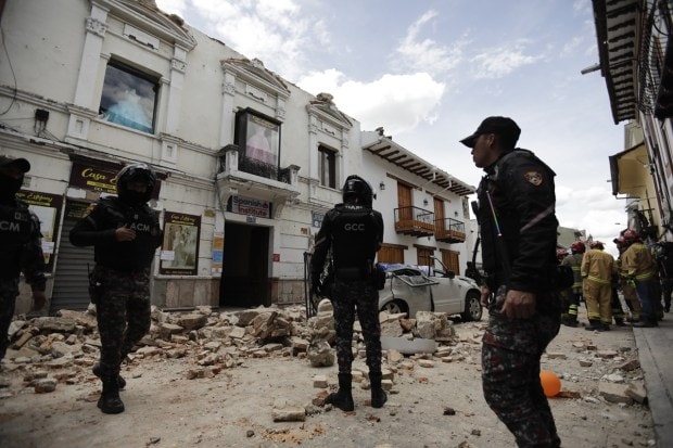Police stand around building damaged after an earthquake struck Cuenca, Ecuador. (AP Photo)