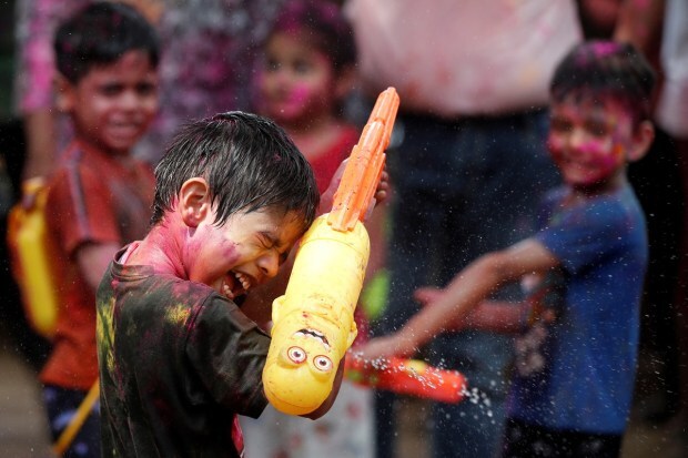 A boy holding a water gun looks away as he’s sprayed with water during Holi celebrations in Mumbai. (Reuters photo)