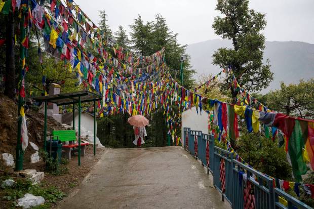 An exile Tibetan Buddhist nun walks in the rain under prayer flags in Dharamshala, India. (AP Photo)