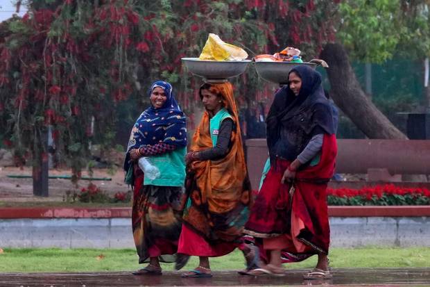 New Delhi: Women walk on the pavement of Kartavya Path amid rainfall, near India Gate in New Delhi. (PTI Photo)