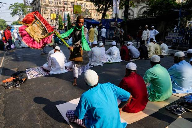 A man with traditional Punkah or a fan blows air to the Muslims gather to offer Eid al-Fitr prayers in Kolkata, India. (AP Photo)