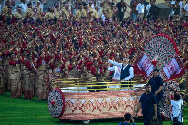Prime Minister Narendra Modi, right, and Assam chief minister Himanta Biswa Sarma wave towards the waiting Assamese dancers and musicians ahead of their performance to attempt Guinness World Record in the largest folk dance performance category in Guwahati, India. (AP Photo)