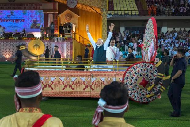Prime Minister Narendra Modi, wave towards the waiting Assamese dancers and musicians ahead of their performance to attempt Guinness World Record in the largest folk dance performance category in Guwahati, India. (AP Photo)