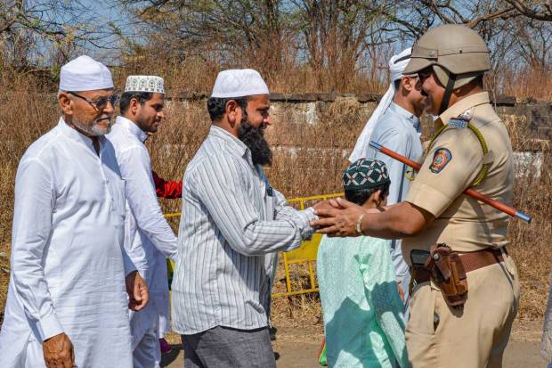 Karad: A police officer greets muslims after they offered 'Namaz' on Eid-ul-fitr, at Idgah Maidan, in Karad. (PTI Photo)
