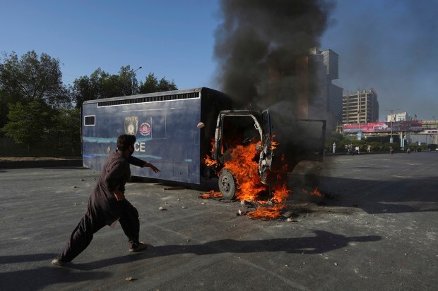 A man runs past a burning prison van set on fire by angry supporters of Pakistan's former Prime Minister. (AP Photo)
