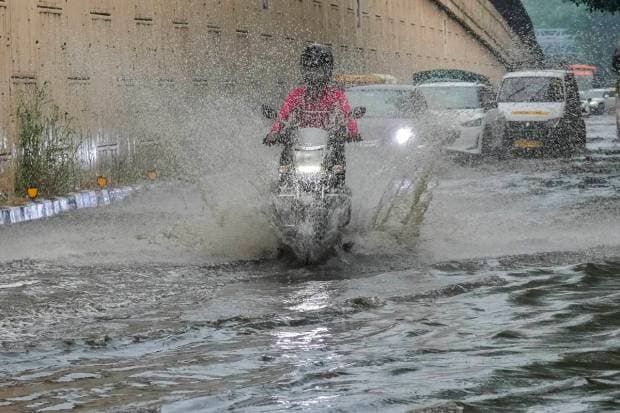 New Delhi: Commuters wade through a waterlogged road following rainfall, in New Delhi. (PTI Photo)