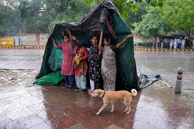 New Delhi: People cover themselves with a plastic sheet during rain at Jantar Mantar, in New Delhi. (PTI Photo)