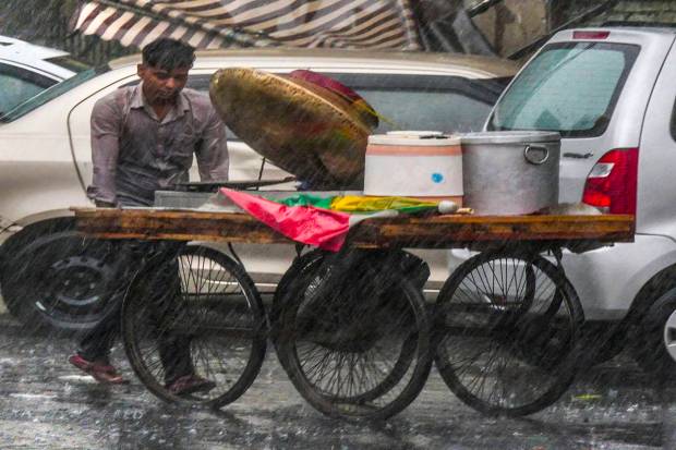 New Delhi: A vendor looks for a shelter during rain, in New Delhi. (PTI Photo)