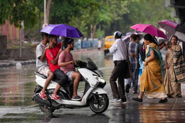 Kolkata: Commuters on a street amid rain, in Kolkata (PTI Photo)
