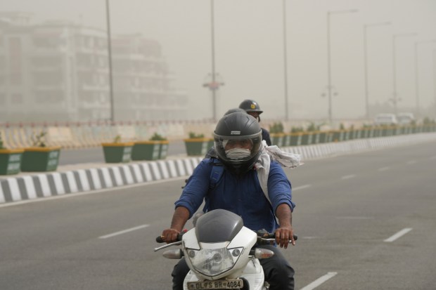A man protecting himself from dust rides his scooter as the air quality deteriorates, in New Delhi. (PTI photo)