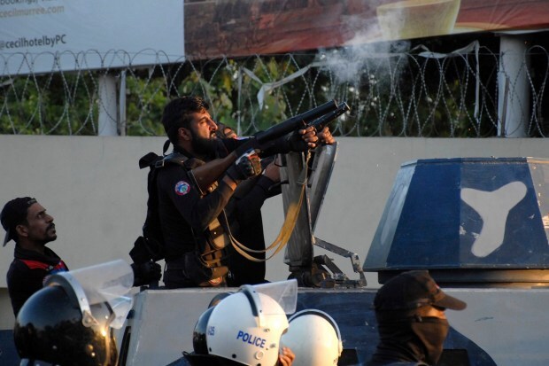 Police officers fire tear gas to disperse supporters of Pakistan's former Prime Minister Imran Khan protesting against the arrest of their leader at an entry gate of the Pakistani army's headquarters, in Rawalpindi, Pakistan. (AP Photo)