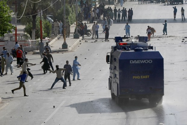 Supporter of Pakistan's former Prime Minister Imran Khan hurl stones at a police vehicle during a protest after Khan's arrest, in Karachi, Pakistan. (Reuters Photo)