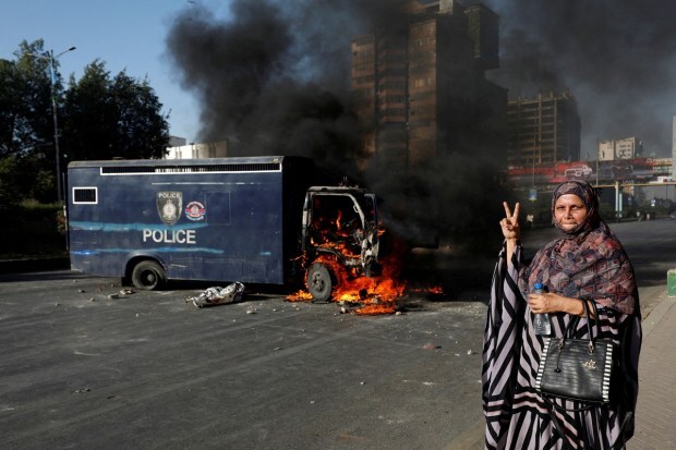 A woman gestures next to a burning police vehicle during a protest by the supporters of Pakistan's former Prime Minister Imran Khan after his arrest. (Reuters Photo)