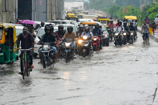 People making their way through a waterlogged road in New Delhi. (Image: PTI)