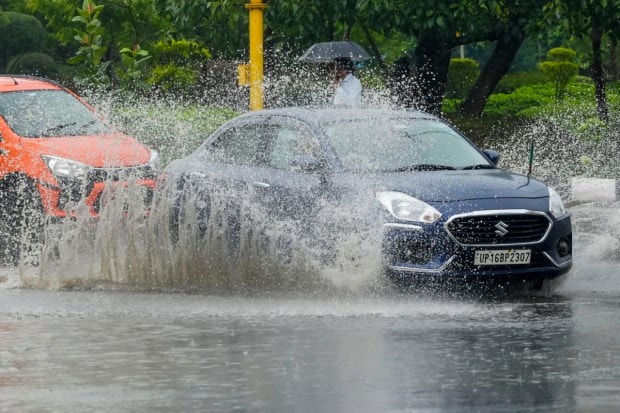 Commuters wade through a waterlogged road during Monsoon rainfall in New Delhi. (Image: PTI)