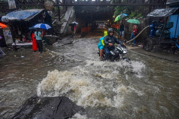 Commuters on a waterlogged road amid rain in Mumbai. (Image: PTI)