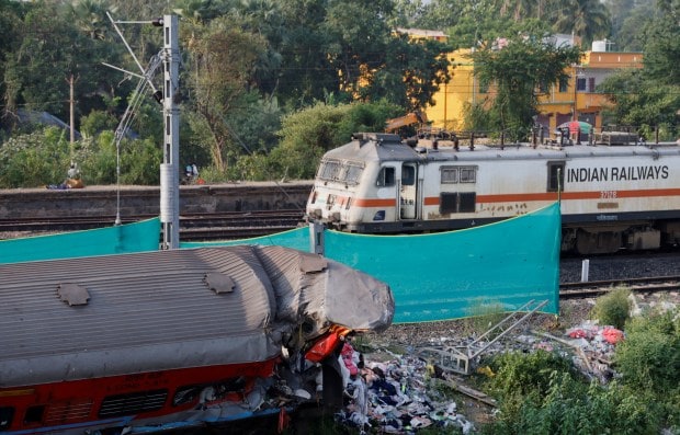 A train moves past a damaged coach, after the tracks were restored, at the site of a train collision. (Reuters Photo)