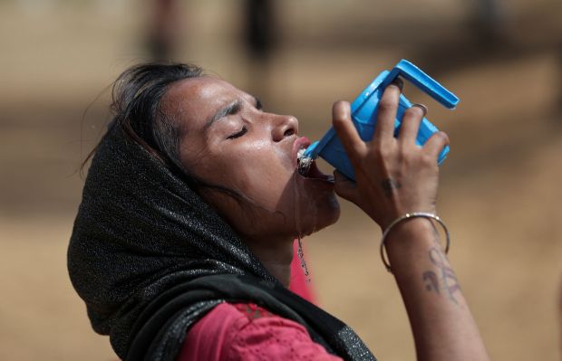 A woman drinks water from a mug on a hot summer day in New Delhi. (Reuters Photo)
