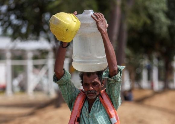 A labourer carries a container filled with water that leaked from a roadside pipe, on a hot summer day in New Delhi. (Reuters Photo)