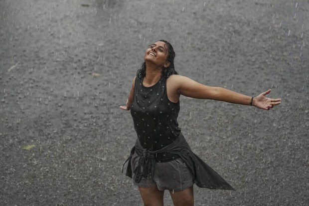 A woman enjoys rain near Chhatrapati Shivaji Maharaj Terminus in Mumbai. (PTI Photo)