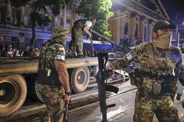 Members of the Wagner Group military company guard an area as other load their tank onto a truck on a street in Rostov-on-Don, Russia. (AP Photo)