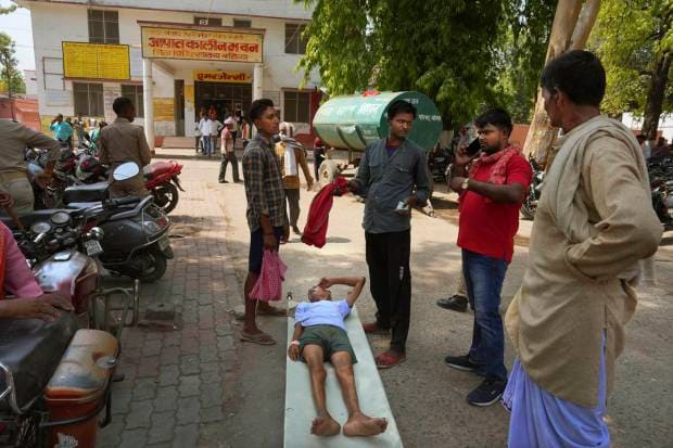 An elderly person suffering from heat related ailment lies on a stretcher waiting to get admitted outside the overcrowded government district hospital in Ballia, Uttar Pradesh state, India. (AP Photo)