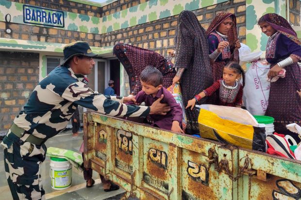 A BSF officer helps a child to get down from a tractor as evacuation process is underway ahead of the expected landfall of Cyclone Biparjoy, at Gunau village of kutch district. So far over 94,000 people have been moved to temporary shelters in eight coastal districts of Kutch, Jamnagar, Morbi, Rajkot, Devbhumi Dwarka, Junagadh, Porbandar and Gir Somnath.(Photo Credits: PTI)