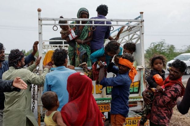 A man carries a child from a truck during an evacuation before the arrival of cyclone Biparjoy in Jakhau in Gujarat. The administration has shifted people from nearly 120 villages located between zero and 10 km from the seashore in Kutch district. (Photo Credits: Reuters)
