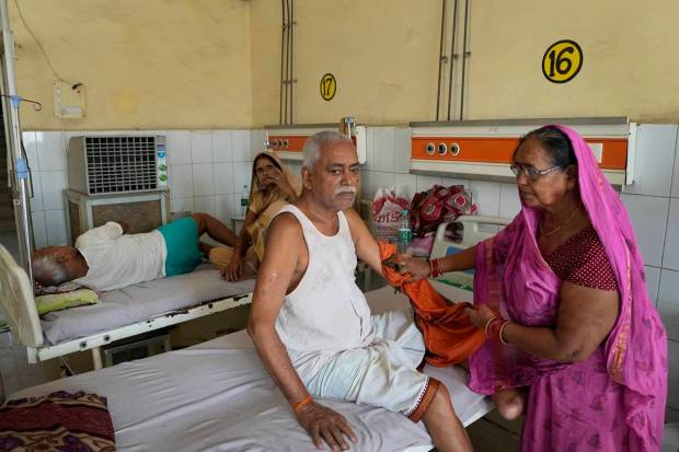 Shiela Mishra wipes the hand of her ailing brother to keep him cool from the heat wave using a wet cloth at the district hospital in Ballia, Uttar Pradesh state, India. (AP Photo)