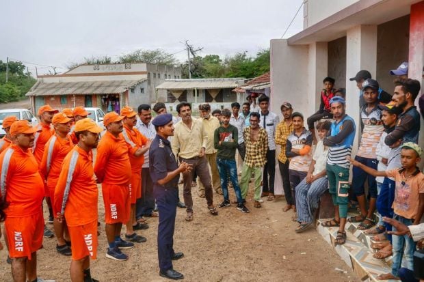 National disaster response force (NDRF) personnel brief citizens ahead of cyclone Biparjoy’s landfall, at Mandvi, in Kutch. A total of 12 teams each of the NDRF and SDRF have been deployed in the districts that are likely to be affected by the cyclone and arrangements have been made for the accommodation, food and medicine of the evacuated people. (PTI Photo)