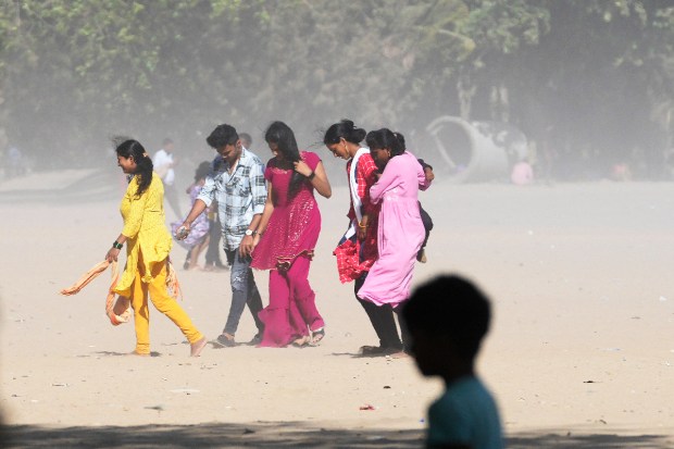 Dust and sand hit people walking on Girgaon beach by the Arabian Sea in Mumbai. The sea has turned rough due to Cyclone Biparjoy. (AP Photo)