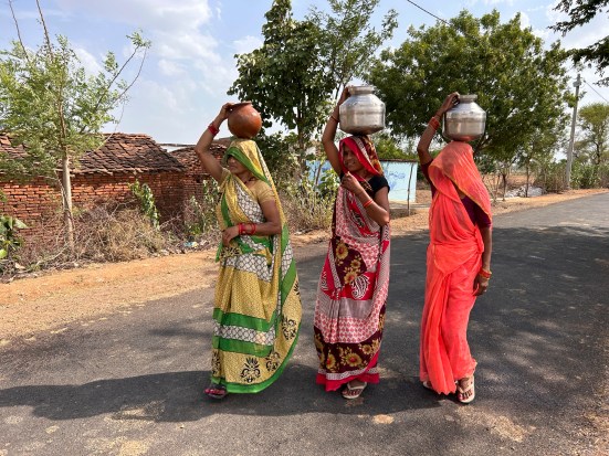 Women walk as they carry pitchers filled with drinking water on a hot summer afternoon in Lalitpur, Uttar Pradesh. (AP Photo)