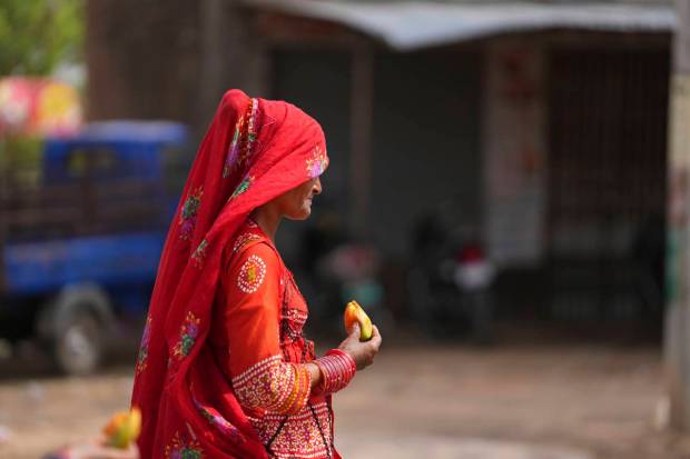 A nomadic woman walks eating a fruit on a hot summer afternoon in Lalitpur district in northern Uttar Pradesh state, India. (AP Photo)