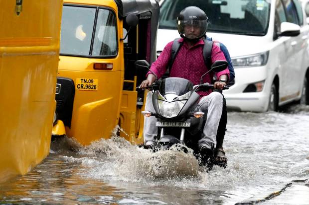 Chennai: Aotorcyclist drives past the waterlogged Rajiv Gandhi IT Expressway after rainfall, in Chennai. (PTI Photo)