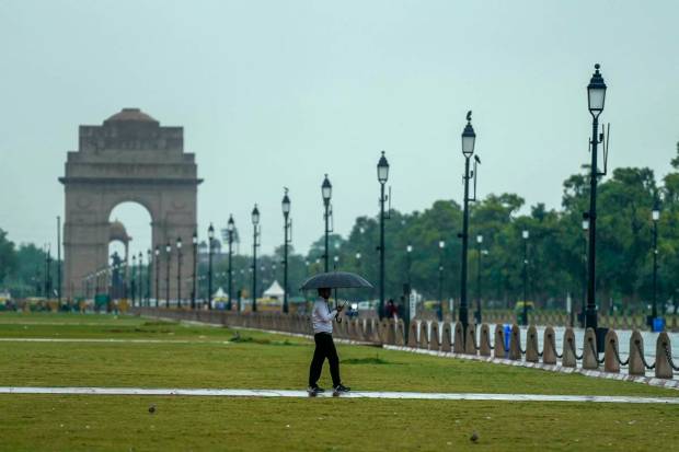 New Delhi: A man walks near India Gate amid light showers, in New Delhi. (PTI Photo)