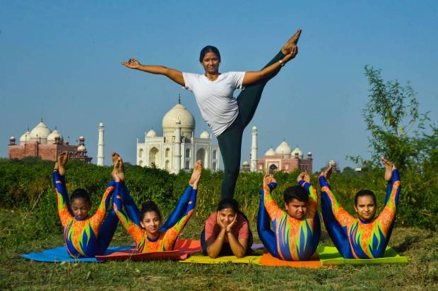 Agra: Children do yoga in the backdrop of Taj Mahal on the eve of the International Day of Yoga, at village Ghadi Chandni in Agra. (PTI Photo)