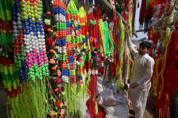 A vendor arranges colorful garlands, ribbons and other items used to decorate the sacrificial animals, at a cattle market set up for the upcoming Muslim Eid al-Adha or Feast of Sacrifice holiday, in Peshawar, Pakistan. (AP Photo)