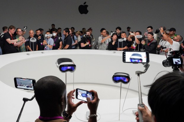 People use phones as Apple's Vision Pro headsets are on display at Apple's annual Worldwide Developers Conference at the company's headquarters in California. (Image: REUTERS)